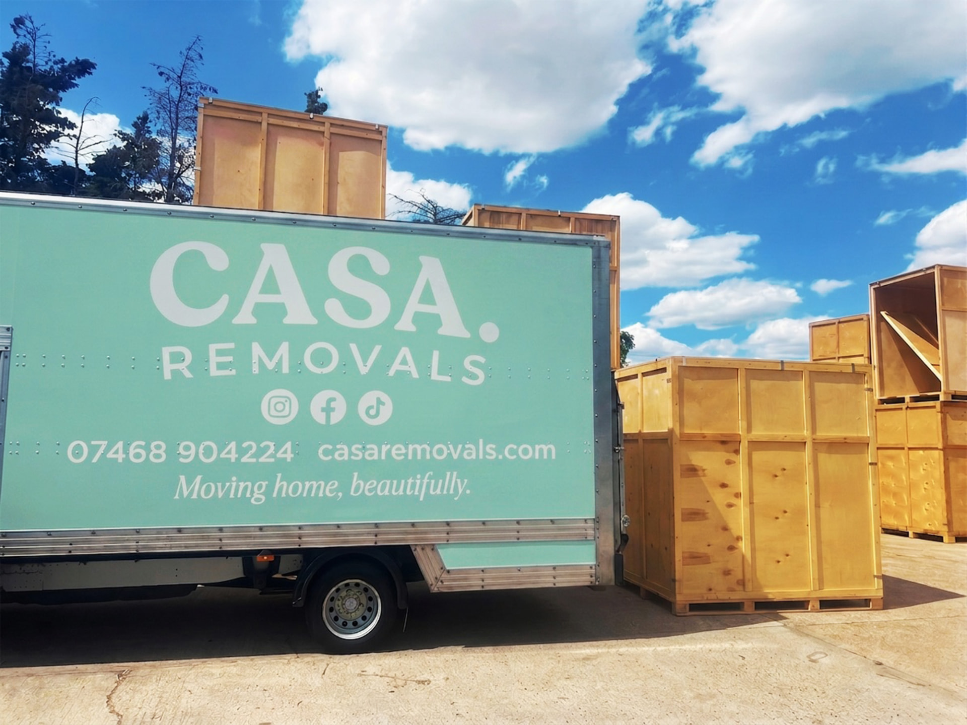 The sage green CASA. removals van beside timber storage containers at the CASA. storage yard